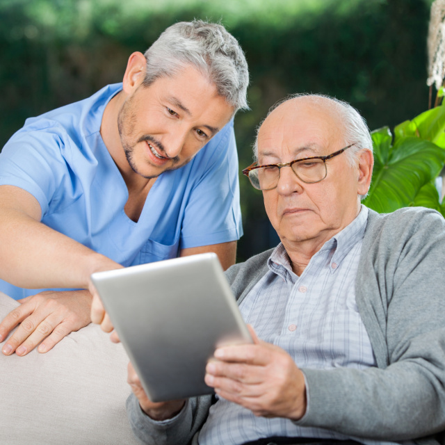 Elderly man with iPad and carer