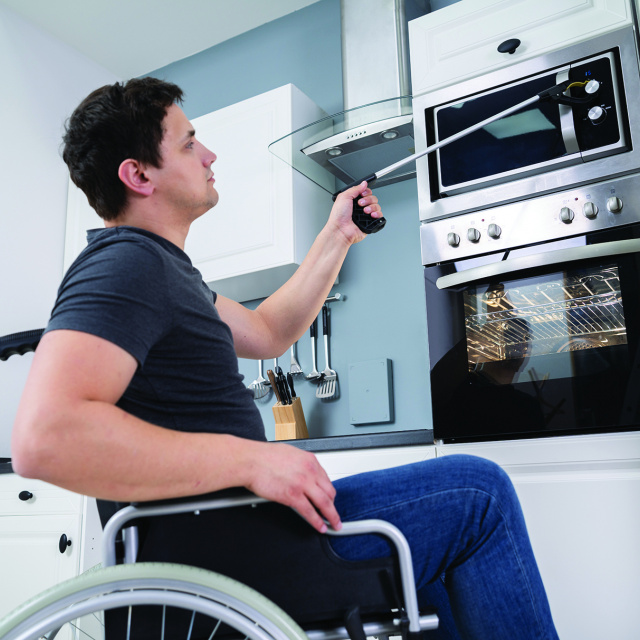 Man in wheelchair in kitchen using small grabber